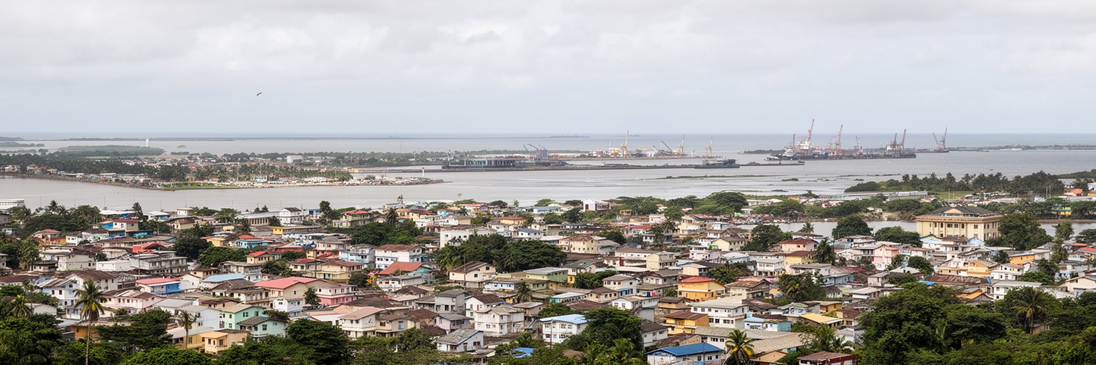 リーブルヴィルの海岸道路、丘陵住宅、雨季の排水、低地の暮らしを表す景観