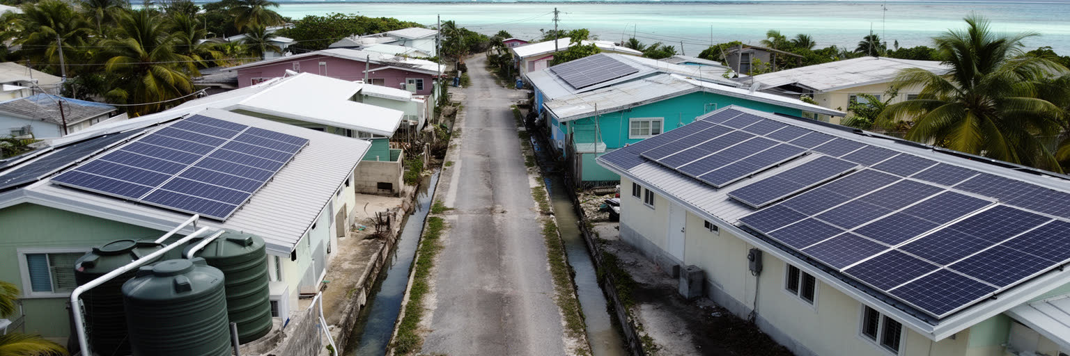 マジュロの住宅、雨水タンク、道路、電力、廃棄物課題を表す景観