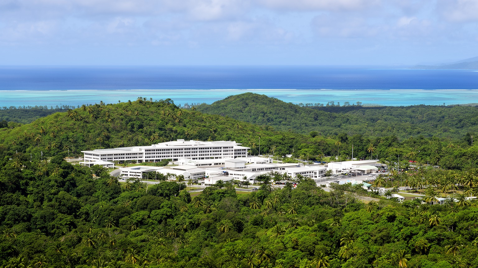 バベルダオブ島の緑、国会議事堂、礁湖が重なるンゲルルムッドの都市景観