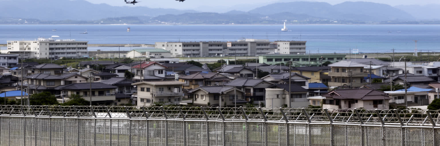 沖縄の米軍基地、フェンス、住宅地、航空機、抗議と日常が重なる基地政治