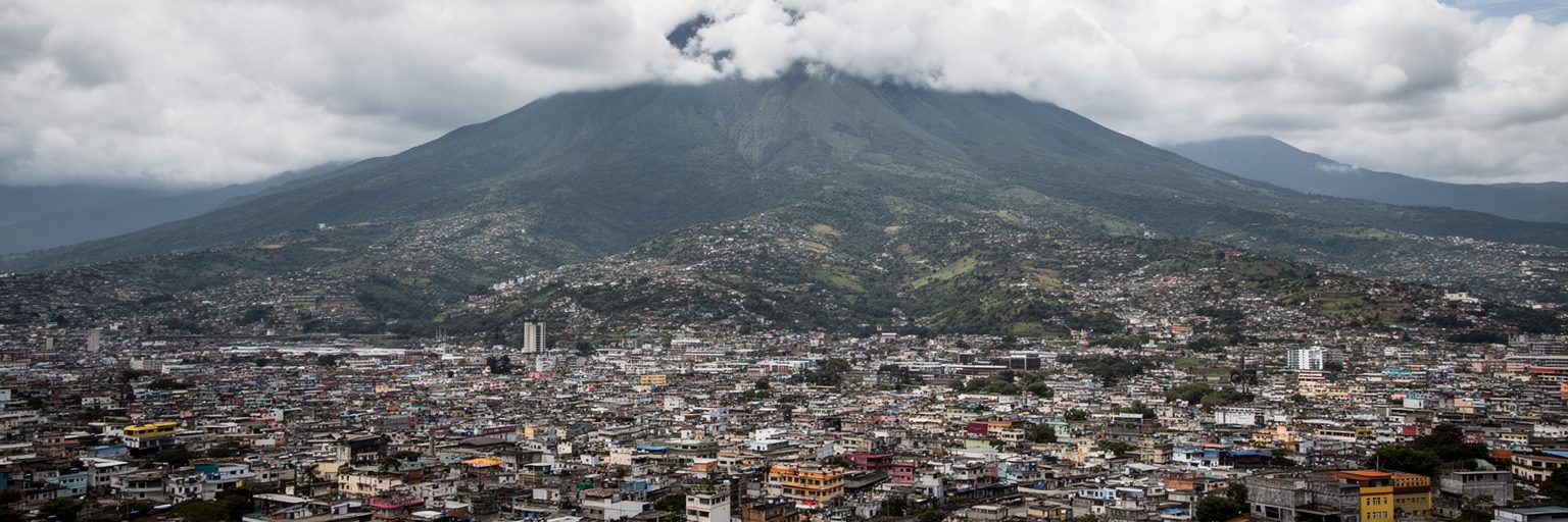 サンサルバドル火山、盆地、市街地、丘陵住宅地、雲のかかる中央高地の景観
